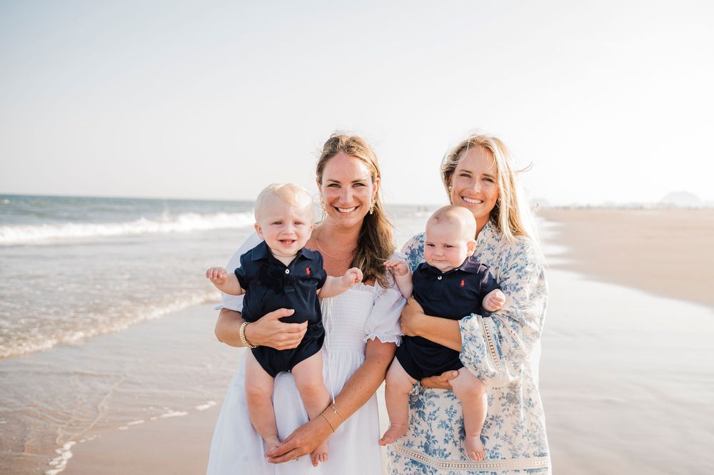 Family group enjoying a beach day together with waves crashing in the background on a sunny afternoon.