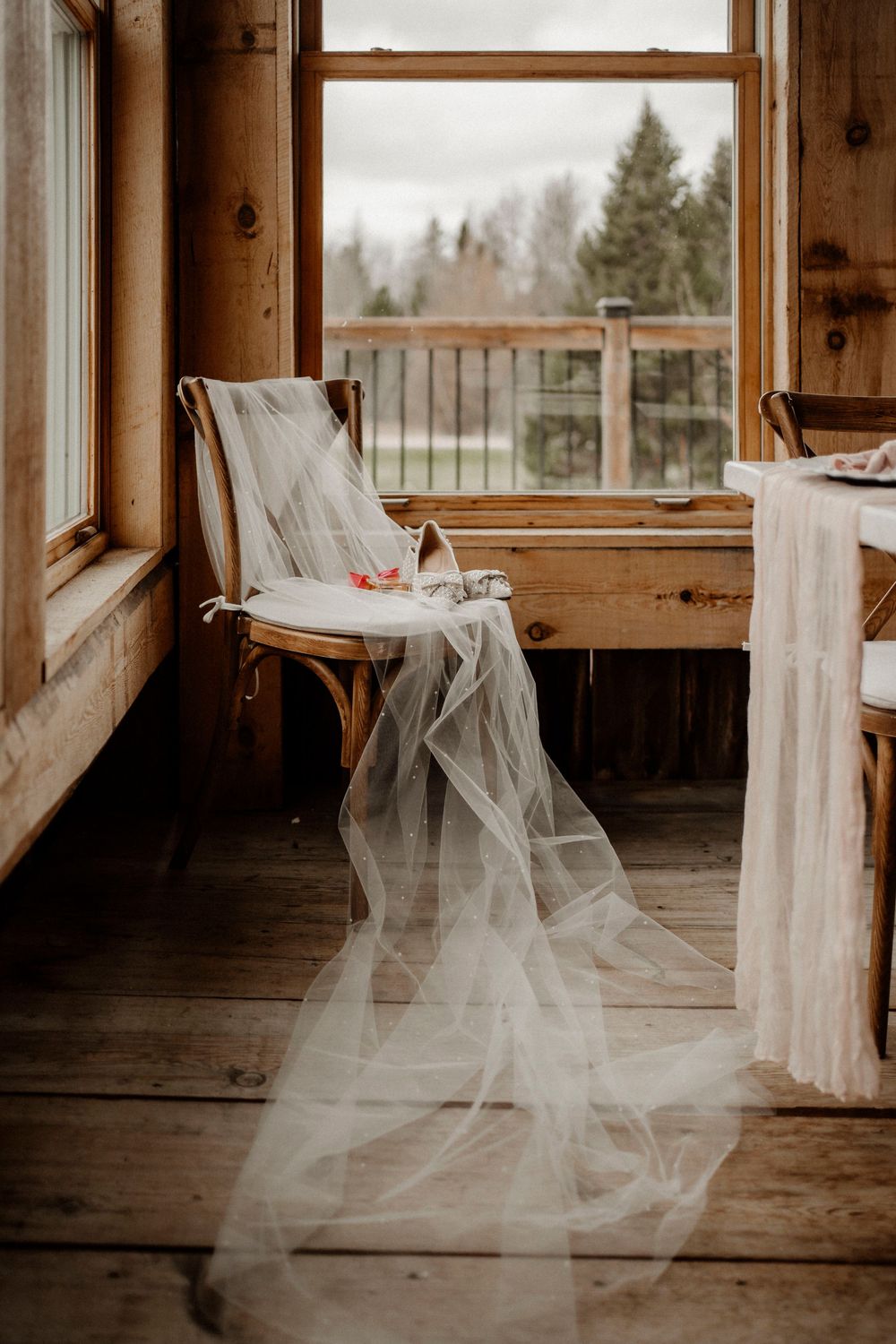 White tulle fabric draped elegantly between wooden beams in a rustic barn venue creating an ethereal wedding atmosphere.