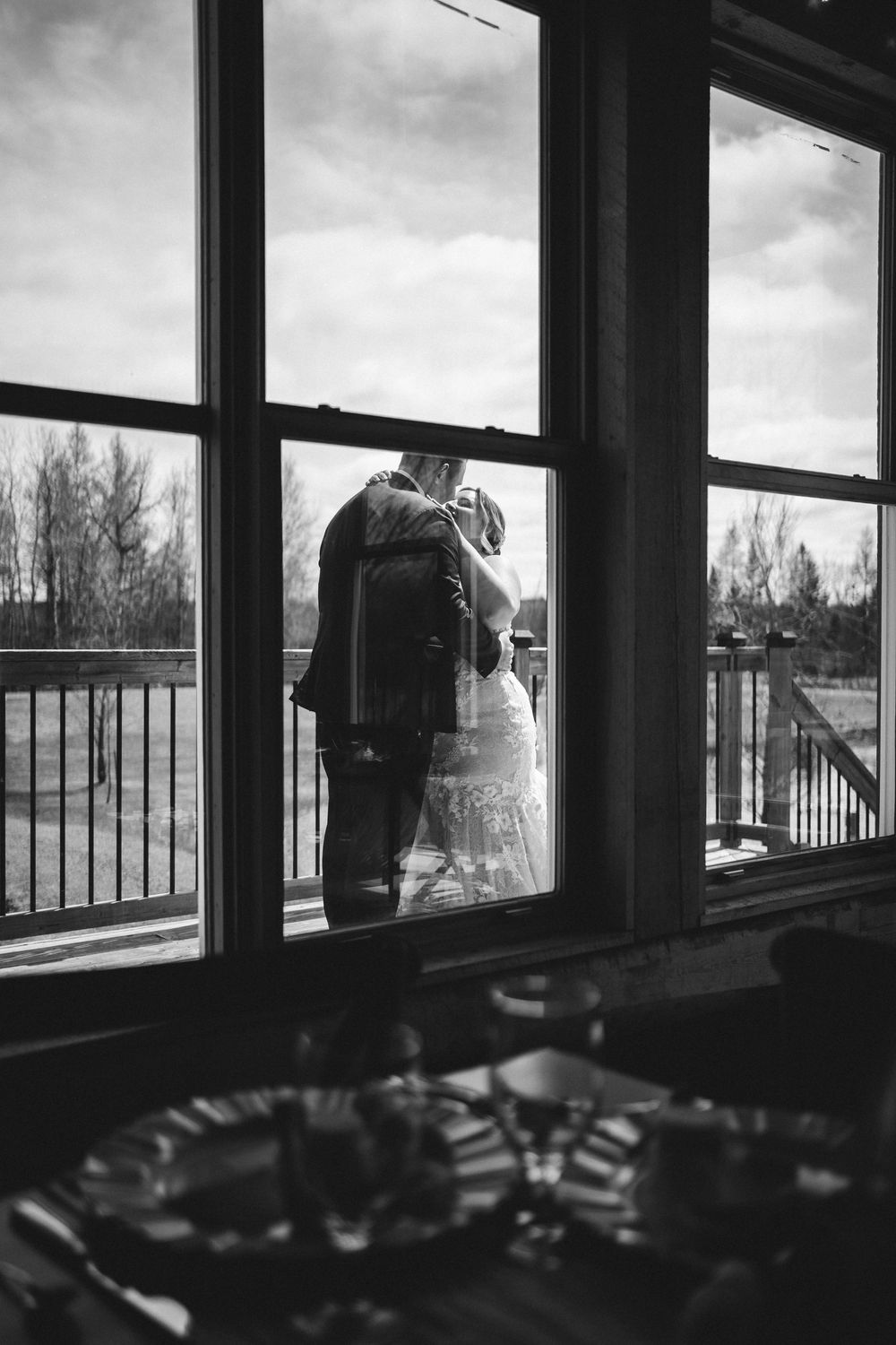 Black and white panorama of a building interior with large windows overlooking trees and winter scenery.