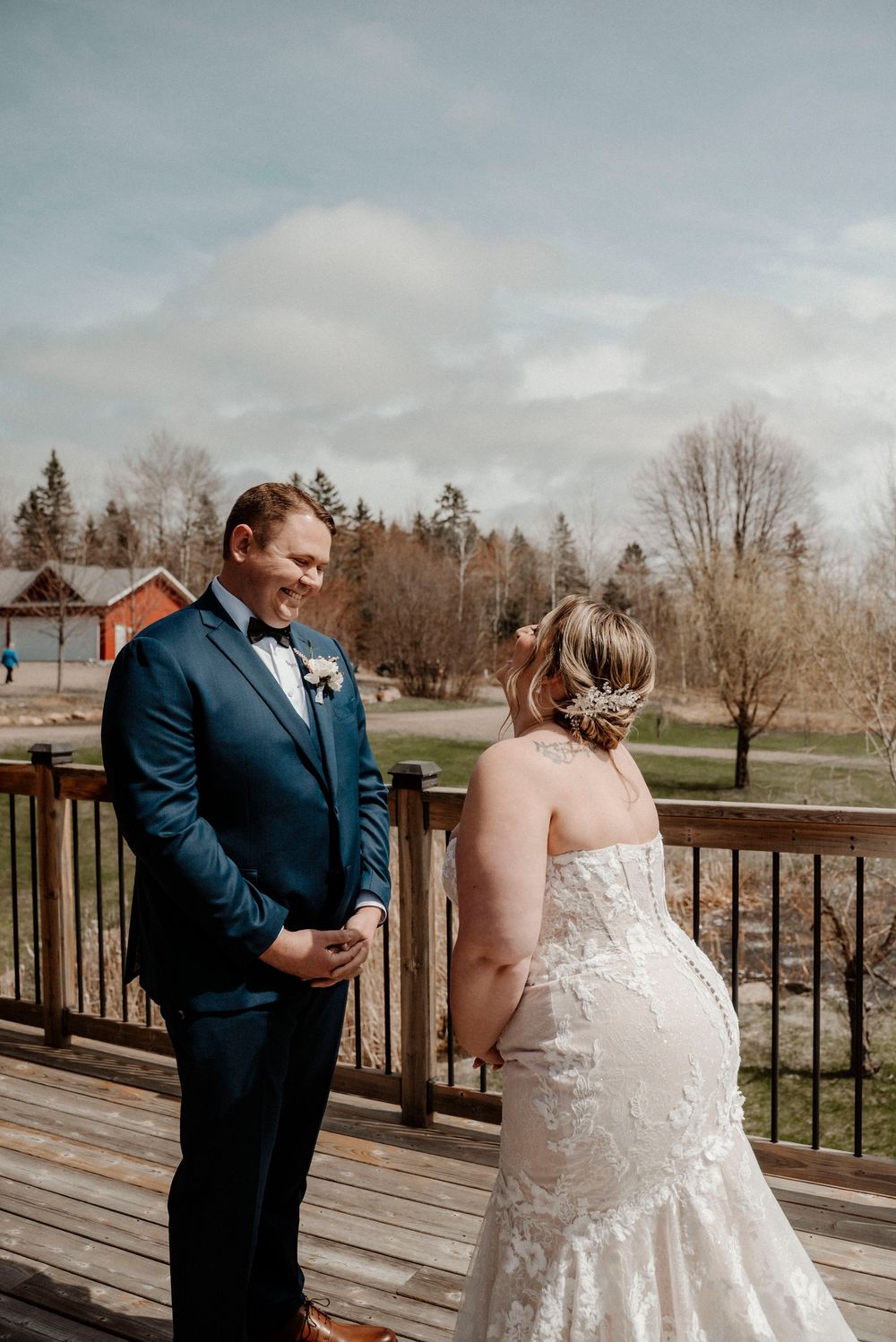 Wedding couple having a first look ceremony on a rustic wooden deck overlooking scenic landscape.