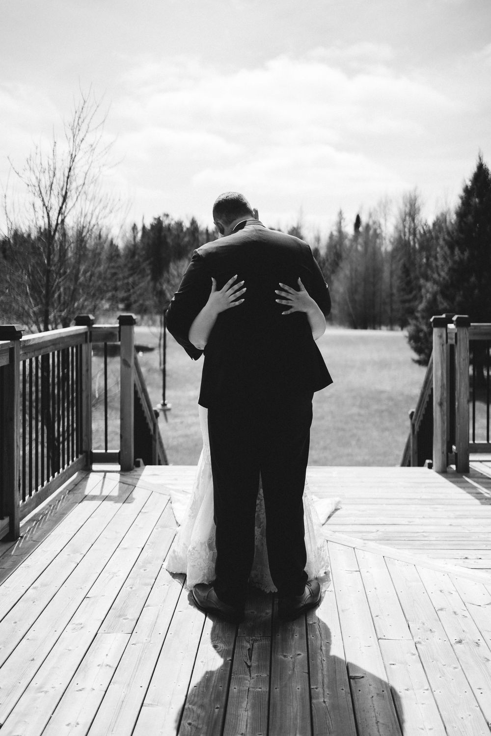 Two people share an intimate dance together on a wooden deck with trees in the background, creating a romantic moment.