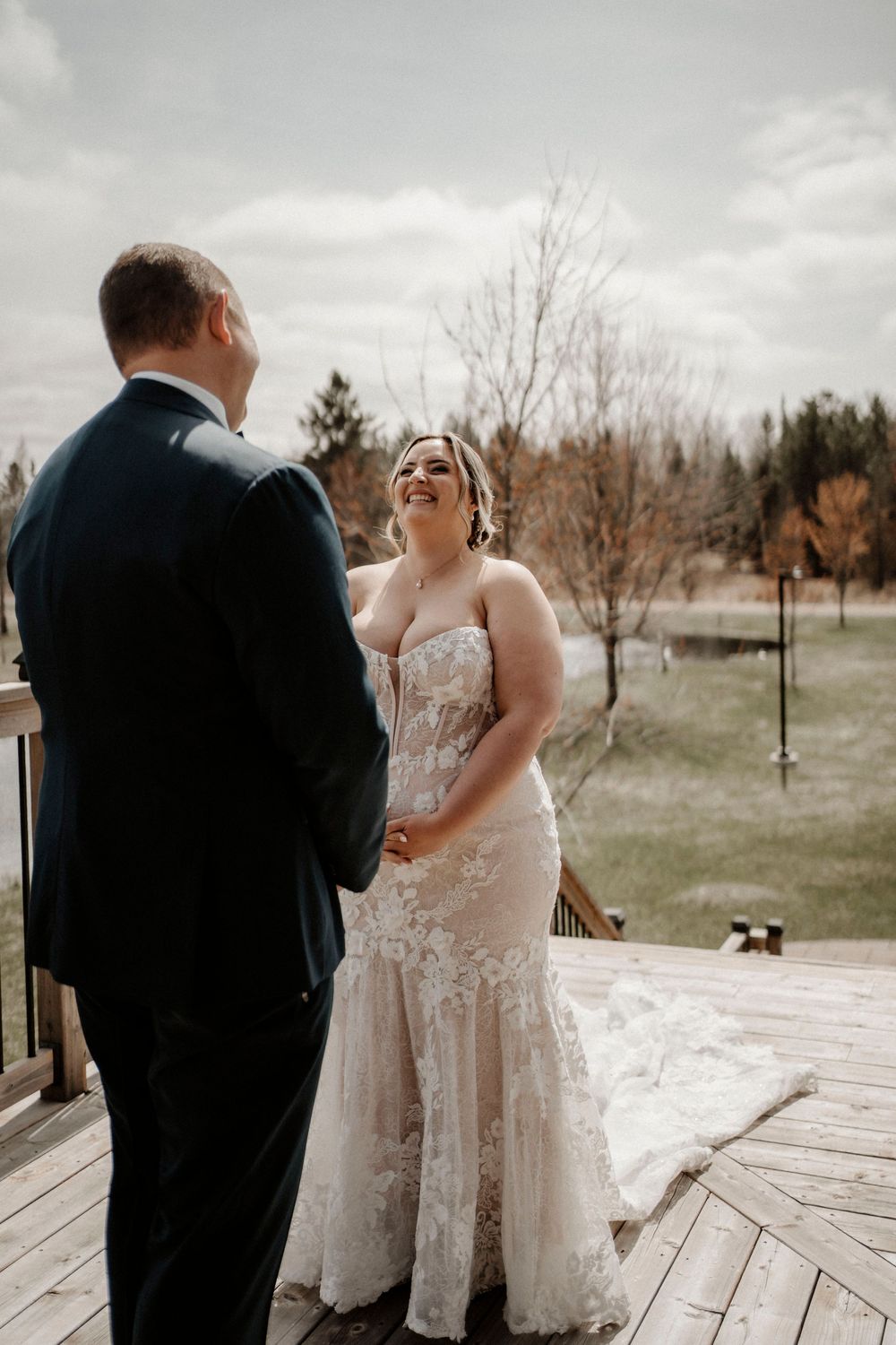 Couple shares intimate first look moment on a wooden deck during their wedding ceremony.