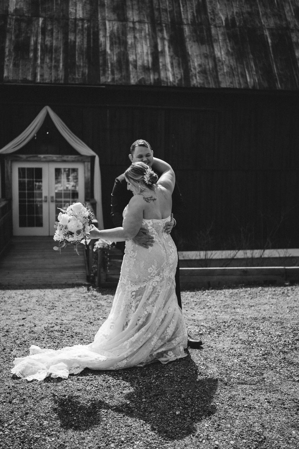 A romantic black and white wedding photo shows a couple embracing against a rustic barn backdrop.