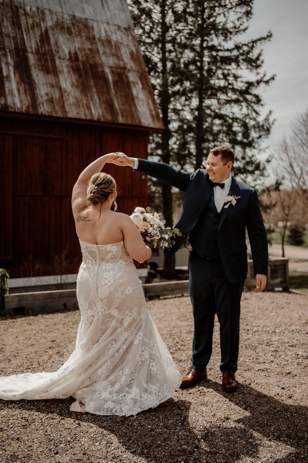 A couple shares a playful first look moment outside a rustic barn on their wedding day.