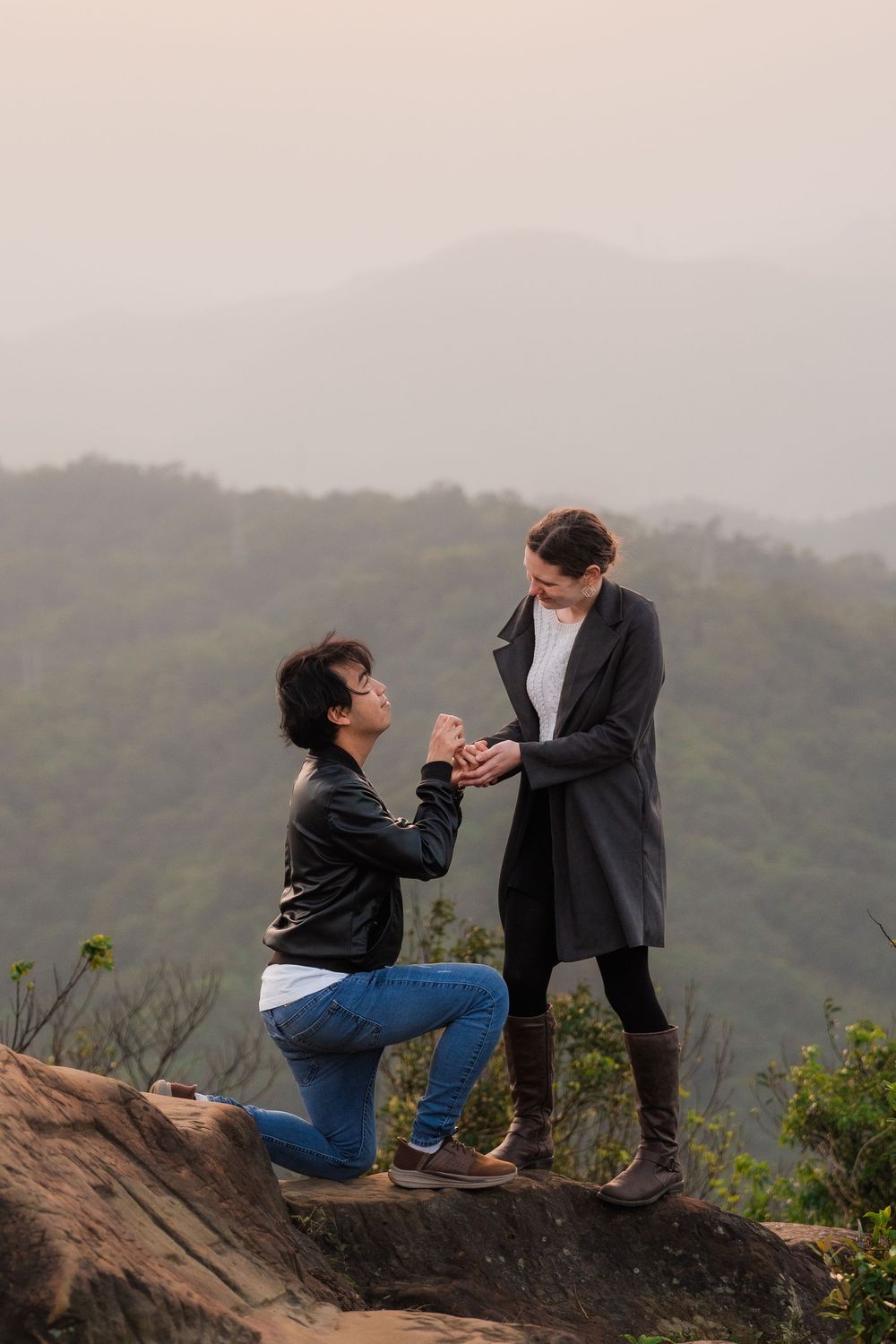 A couple's romantic proposal on Thumb Lookout Mountain overlooking misty hills in the background.