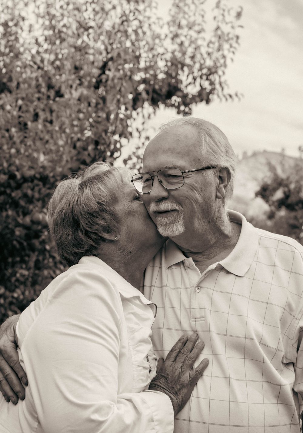 Sweet candid moments captured between two people in white clothing outdoors.