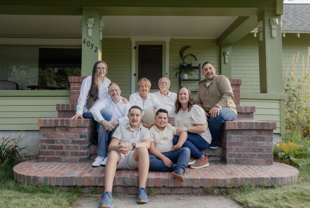 Family members relaxing and posing casually on front porch steps of a house.
