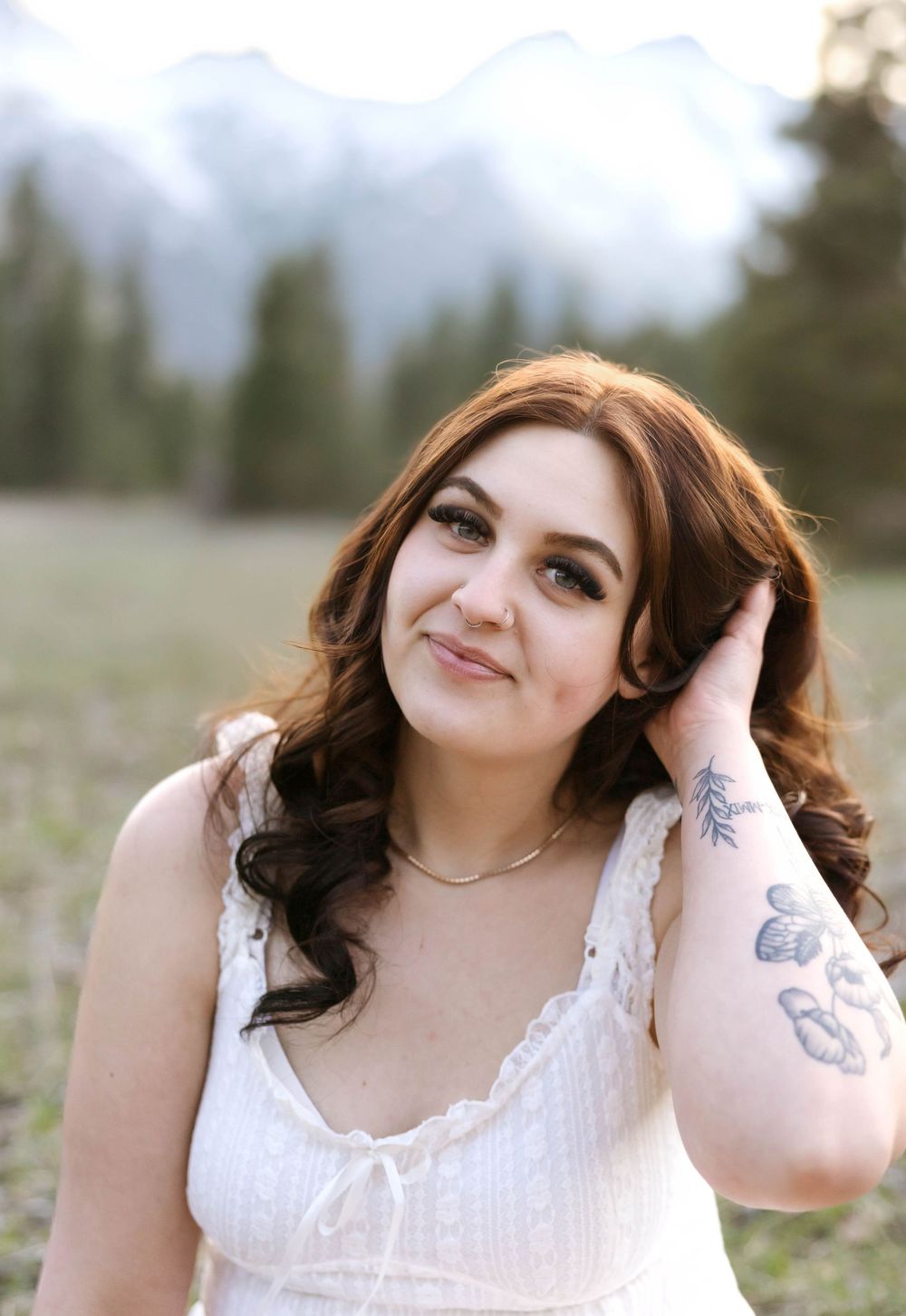 Portrait in white dress with mountain vista and meadow backdrop.