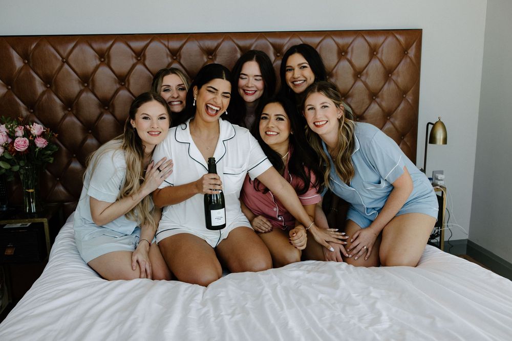 Group relaxing on bed during wedding preparations.