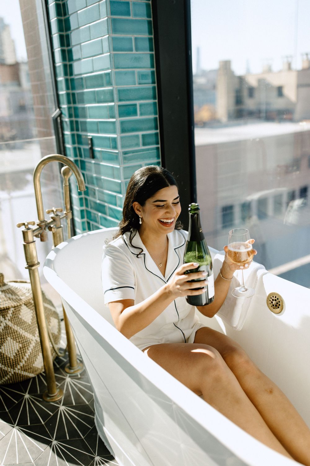 Relaxing bathtub moment with champagne glass and city skyline views.