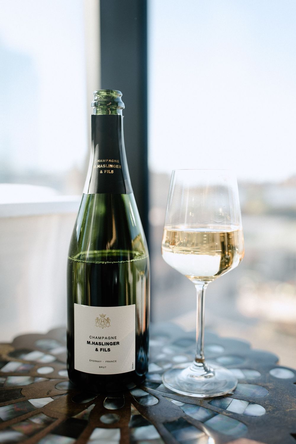 Champagne bottle and wine glass on dark surface with blurred background.