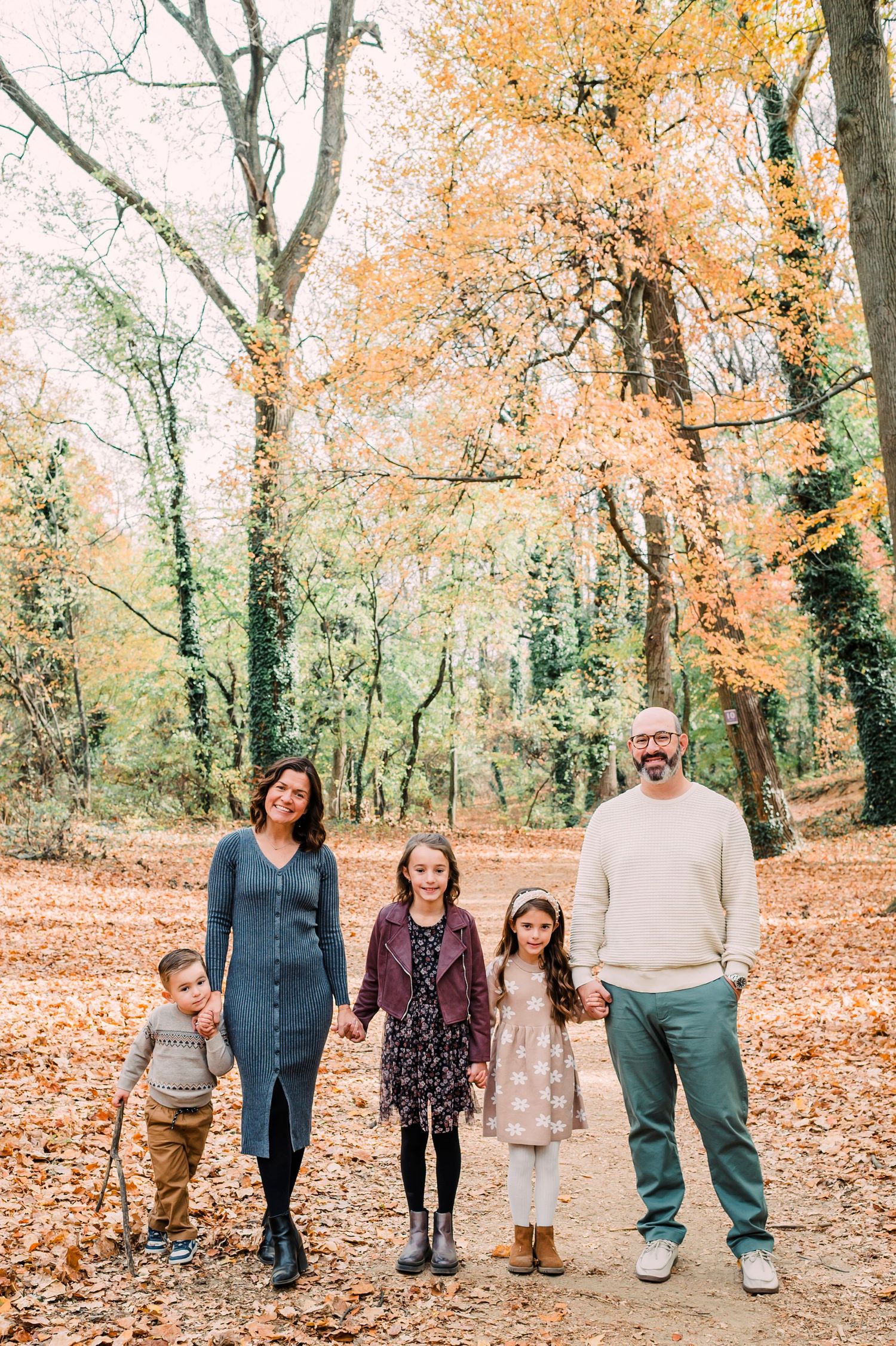 A joyful family shares a tender moment together against a backdrop of colorful flower garlands at an outdoor setting.
