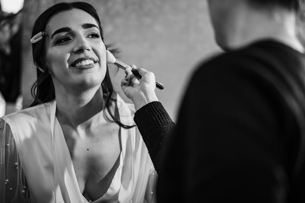 Black and white photo showing final touches being applied during wedding preparation.