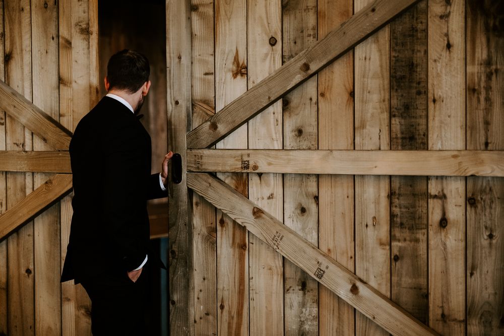 A rustic wooden barn door interior creates a natural backdrop for a wedding setting.