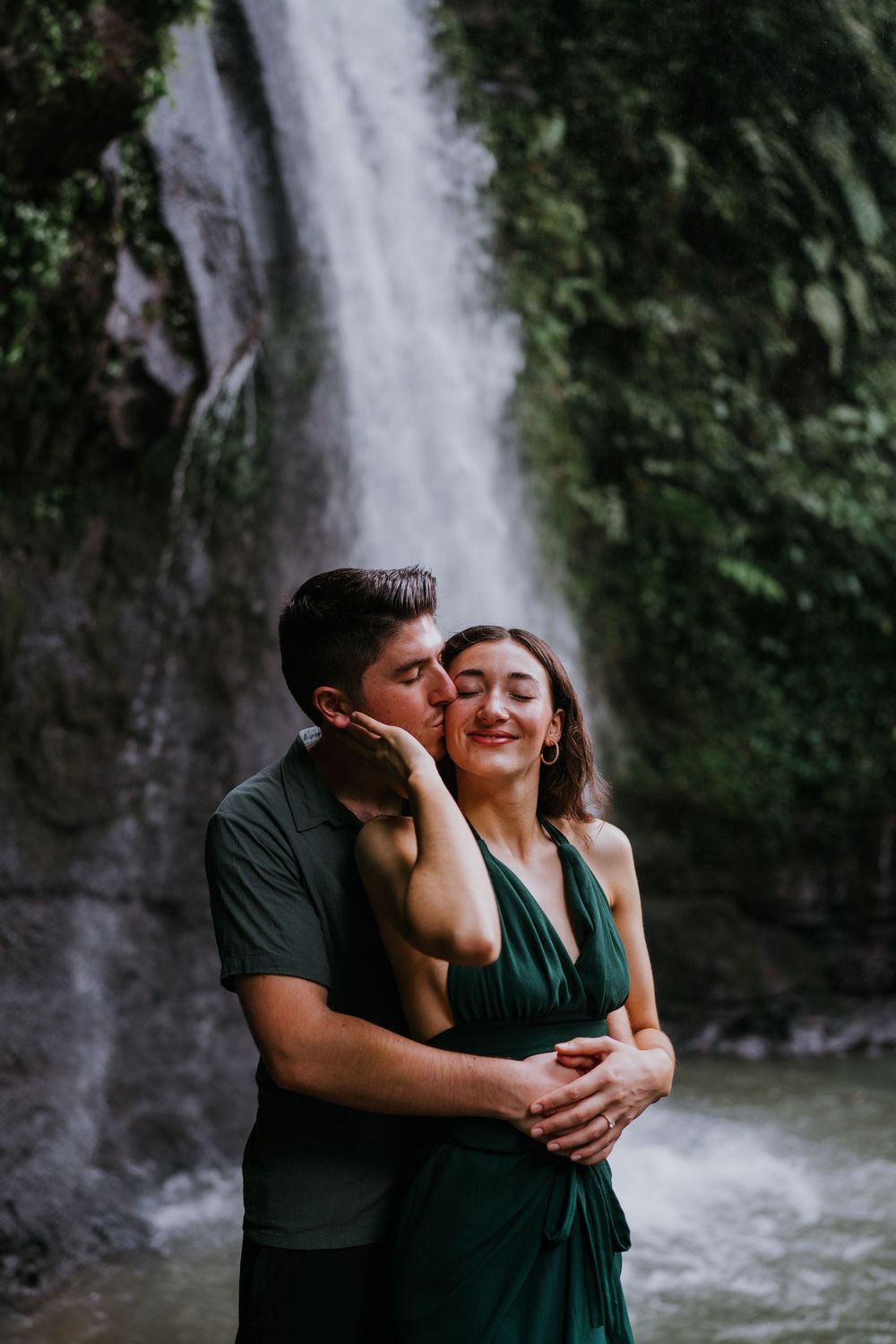 Intimate moments captured between a couple with a majestic waterfall backdrop.