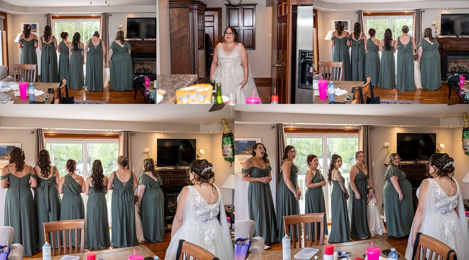 Wedding party poses together in formal attire in front of large windows in a reception venue.