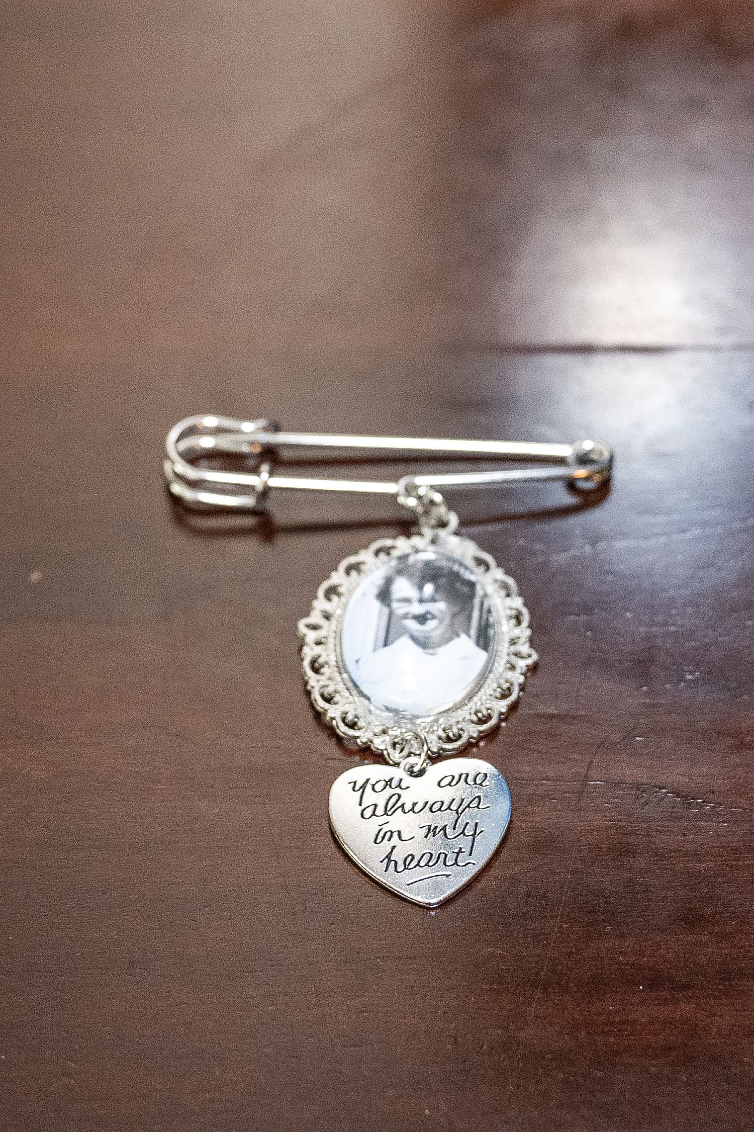 A collection of delicate silver bracelet charms laid out in sequence on a dark wooden surface.