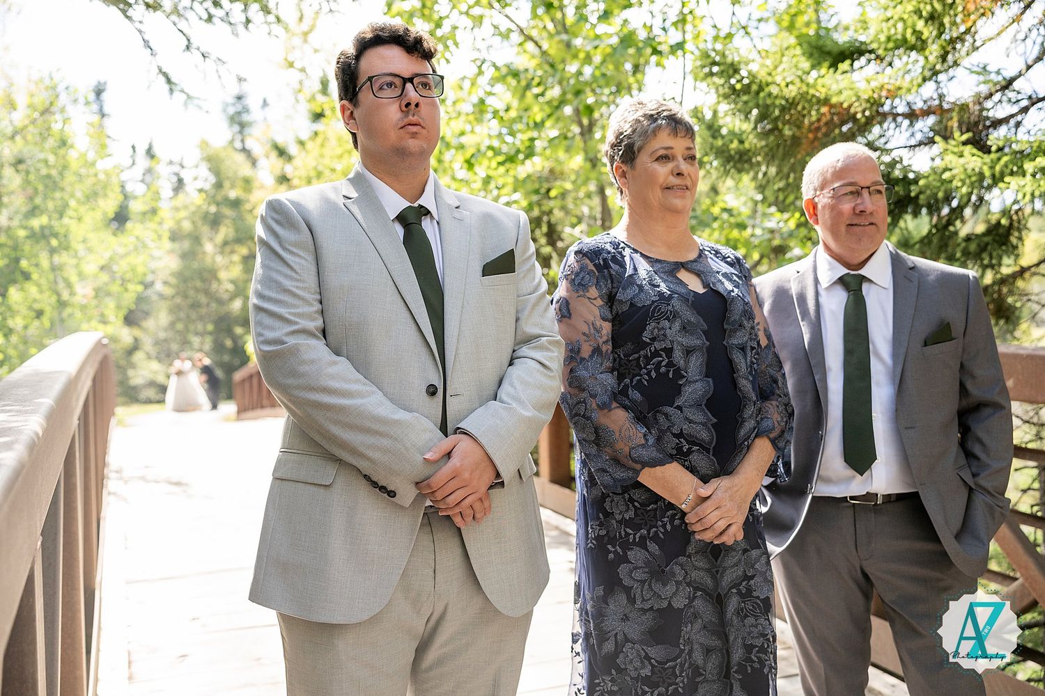 Wedding party members gather outdoors in formal attire on a sunny day.