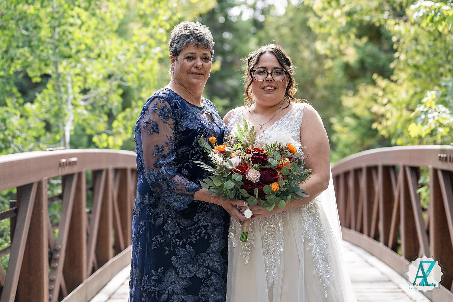 Bridal party standing on wooden bridge with forest backdrop and natural lighting.
