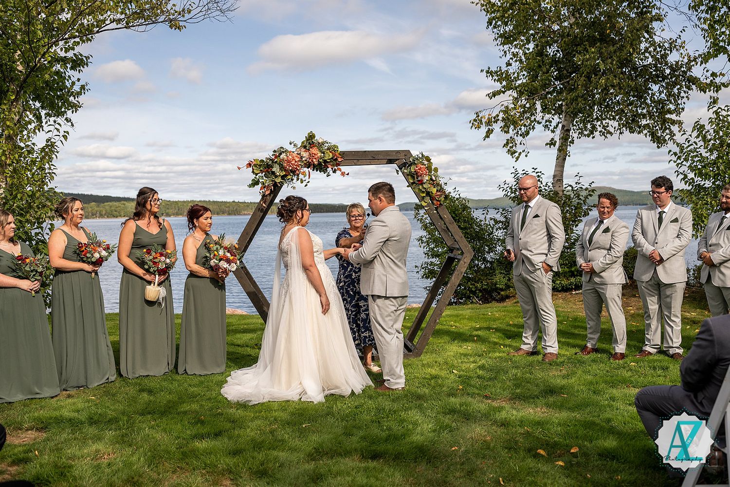 A wedding bridal party poses for sunset portraits in a line on a hilltop overlooking a scenic vista.