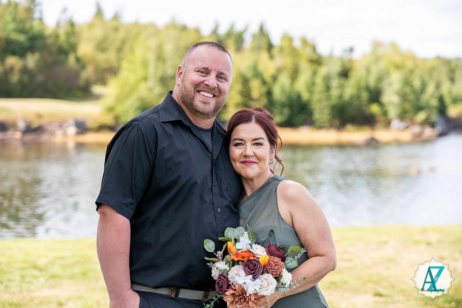 Outdoor wedding portraits taken in front of a scenic lake and tree-lined shore.