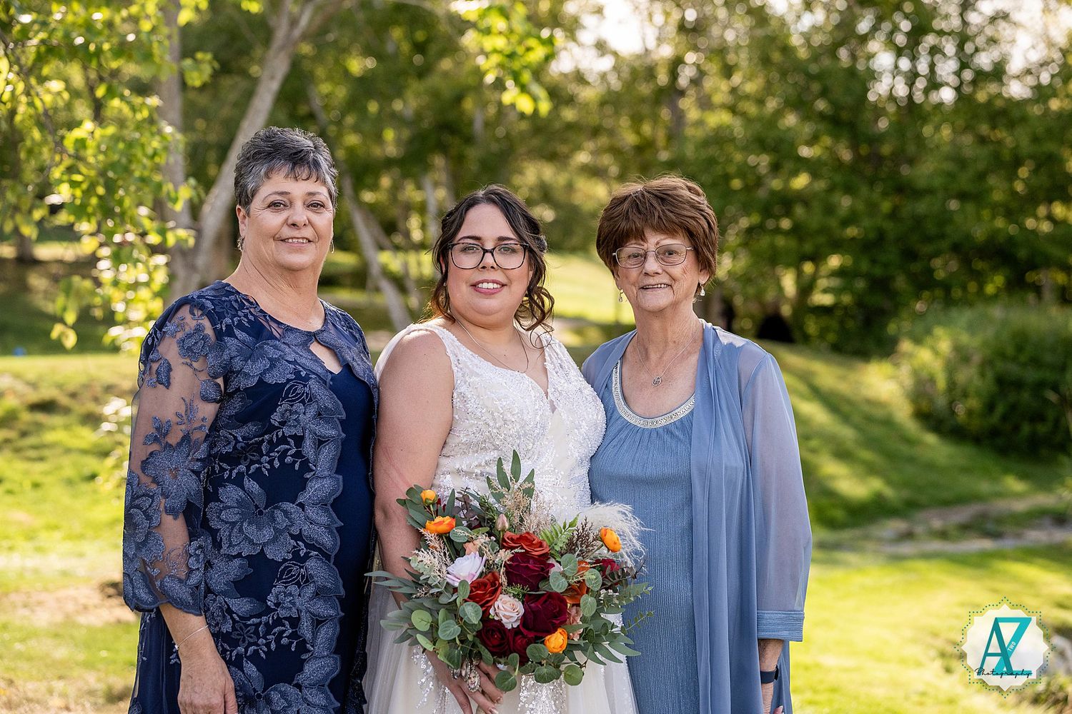 A wedding party poses together in an outdoor garden setting with colorful floral bouquets during golden hour.