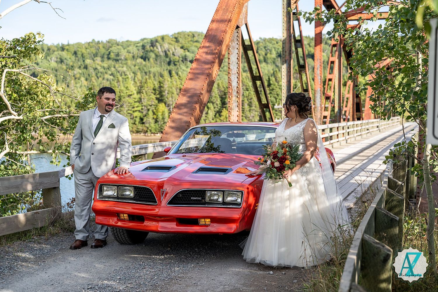 Classic red sports cars parked along scenic mountain road during wedding photography shoot.