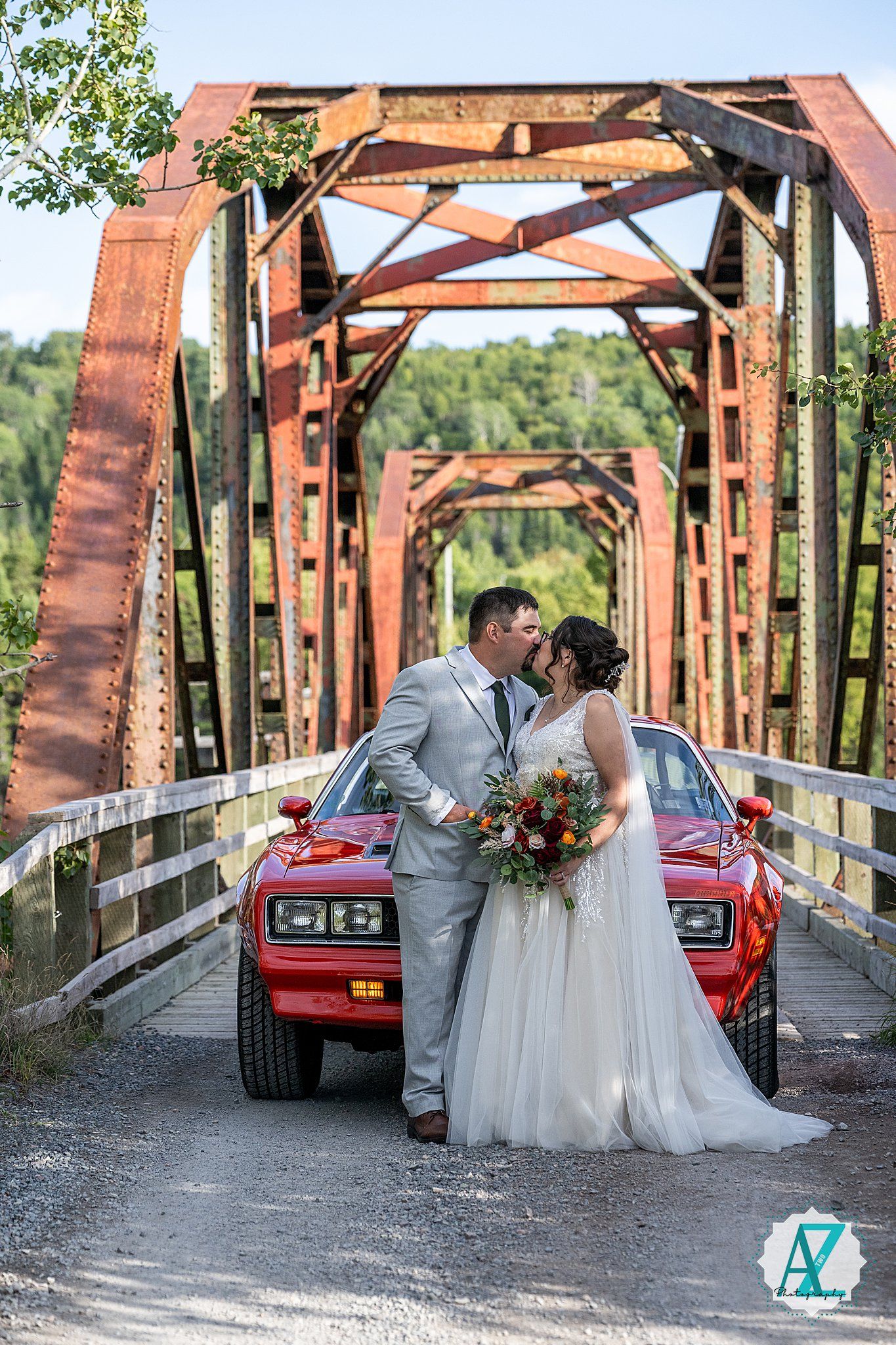 A romantic bride and groom pose with their red vintage Ferrari on a rustic covered bridge in a series of wedding photos.