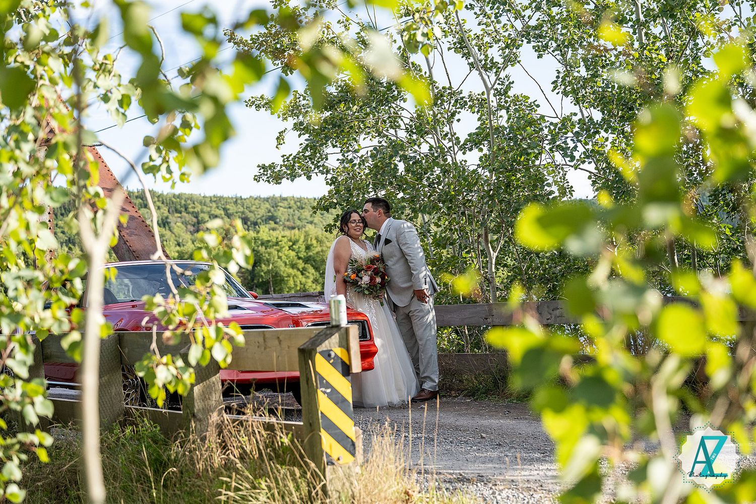 A couple shares an intimate moment during their wedding ceremony in a lush garden setting with a decorative wagon.