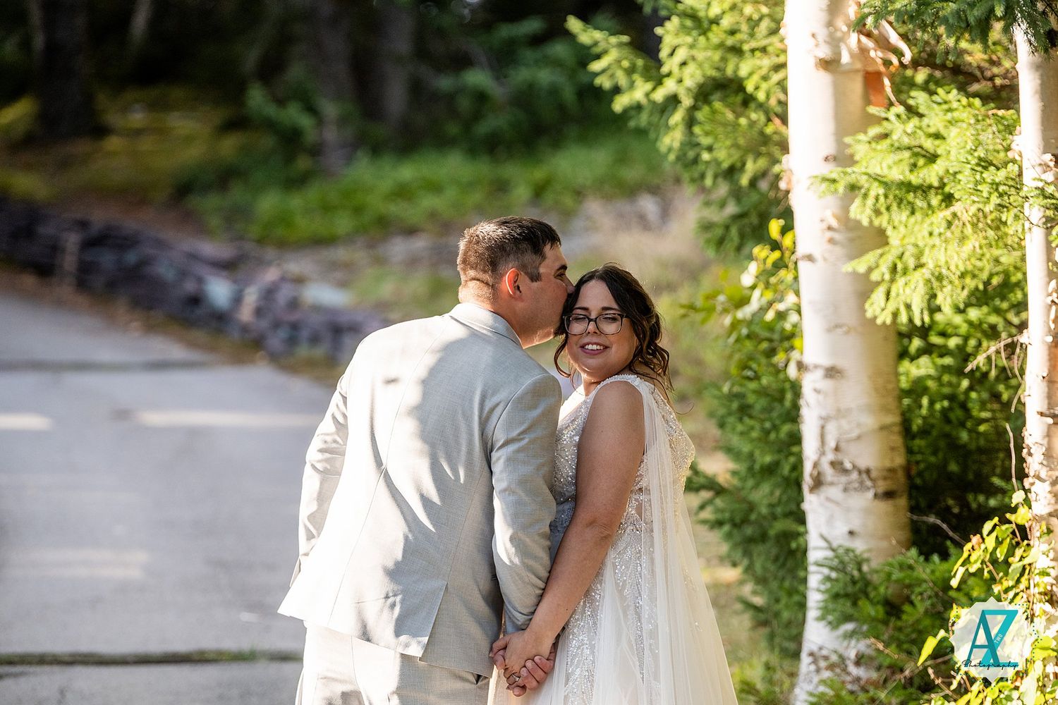 Elegant couple sharing romantic moments along a sunlit tree-lined pathway.