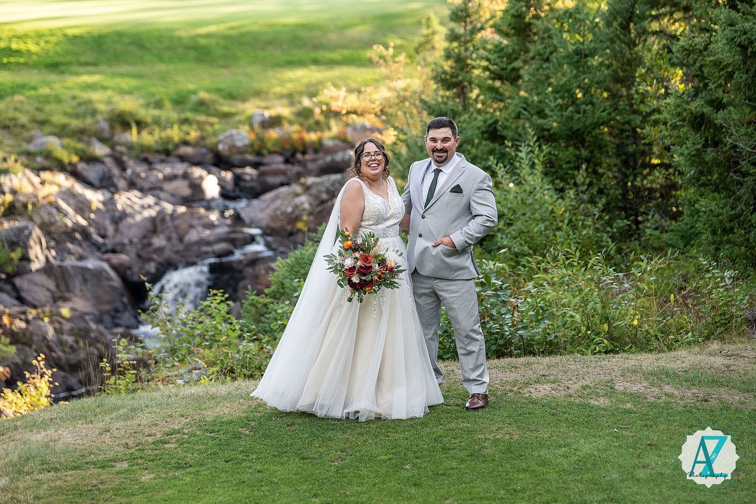 A romantic outdoor wedding scene in a lush green field with mountains and natural scenery in the background.