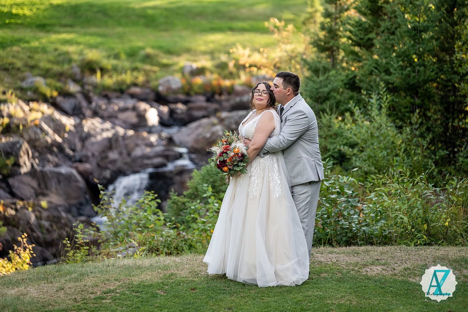 Couple in wedding attire sharing intimate moments on a green hillside with natural landscape.