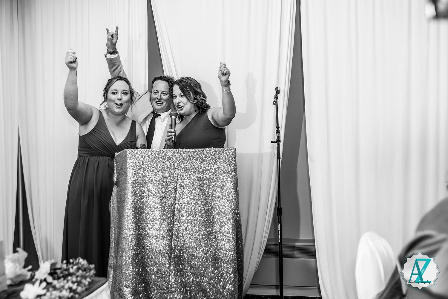 Black and white photo of wedding guests celebrating enthusiastically at a podium.