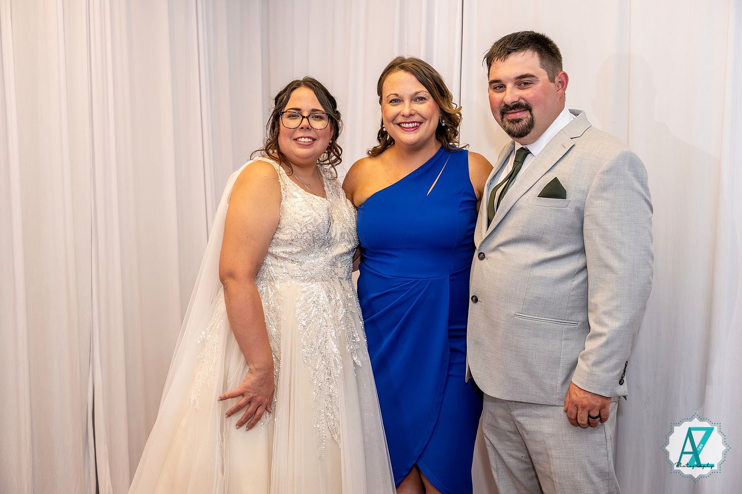 Elegant wedding party members pose together in coordinated royal blue and gray attire against white backdrop.