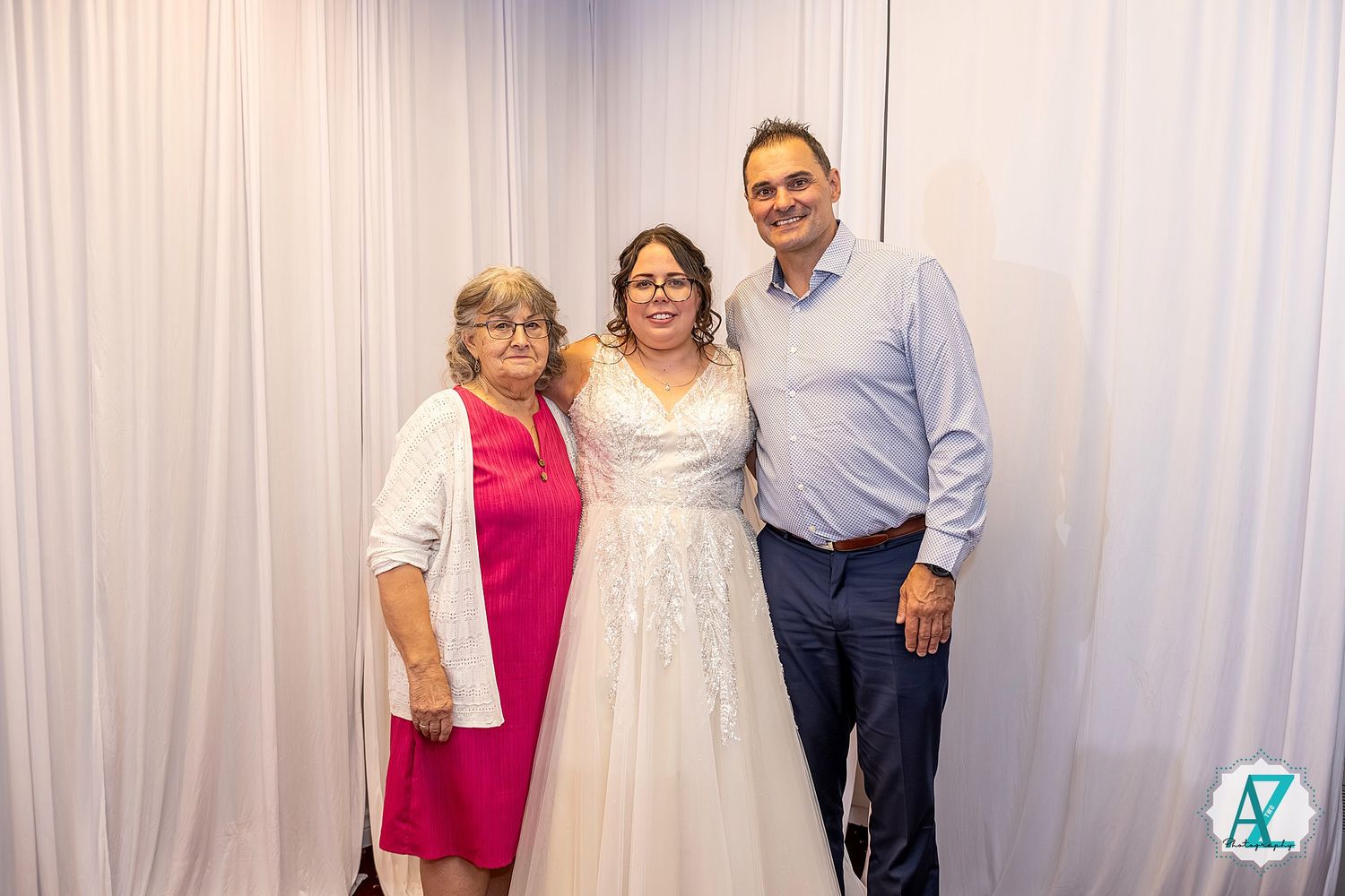 Several people stand together smiling in front of a white curtain at what appears to be a celebration.