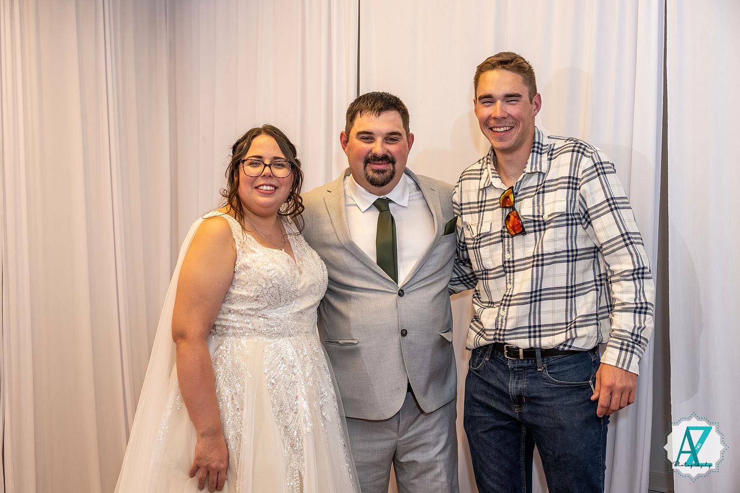 Guests gather at a wedding celebration wearing formal attire against a light backdrop.