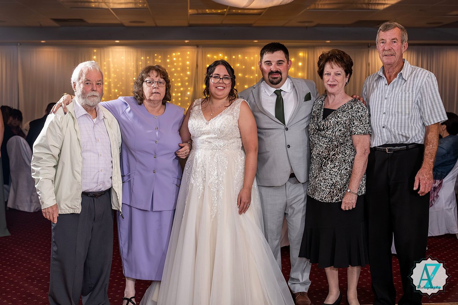 Wedding celebration scene with guests in formal wear gathered inside an elegantly decorated venue.
