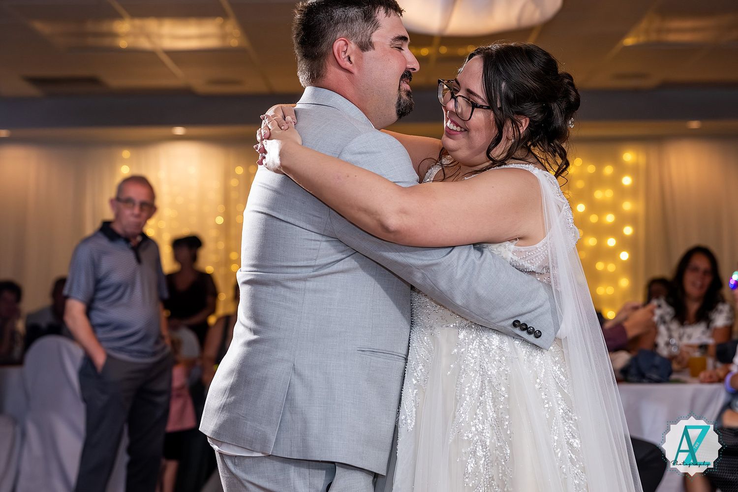 Wedding party on dance floor during reception under warm lighting in decorated ballroom.