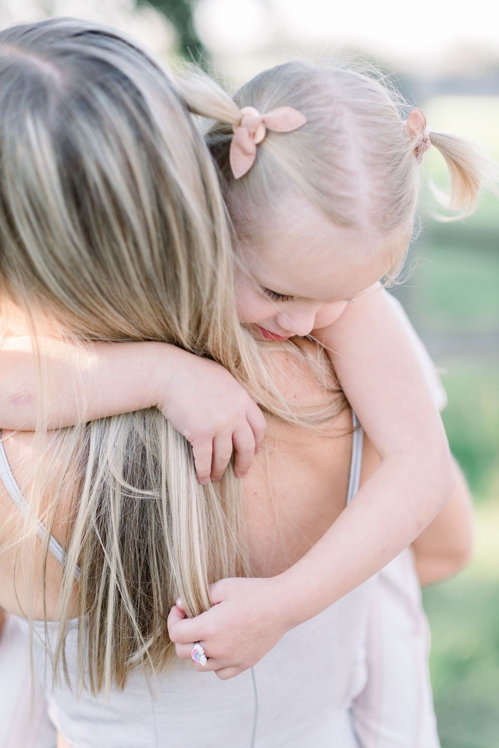 A tender moment between two people in light colored clothing against a soft natural background.