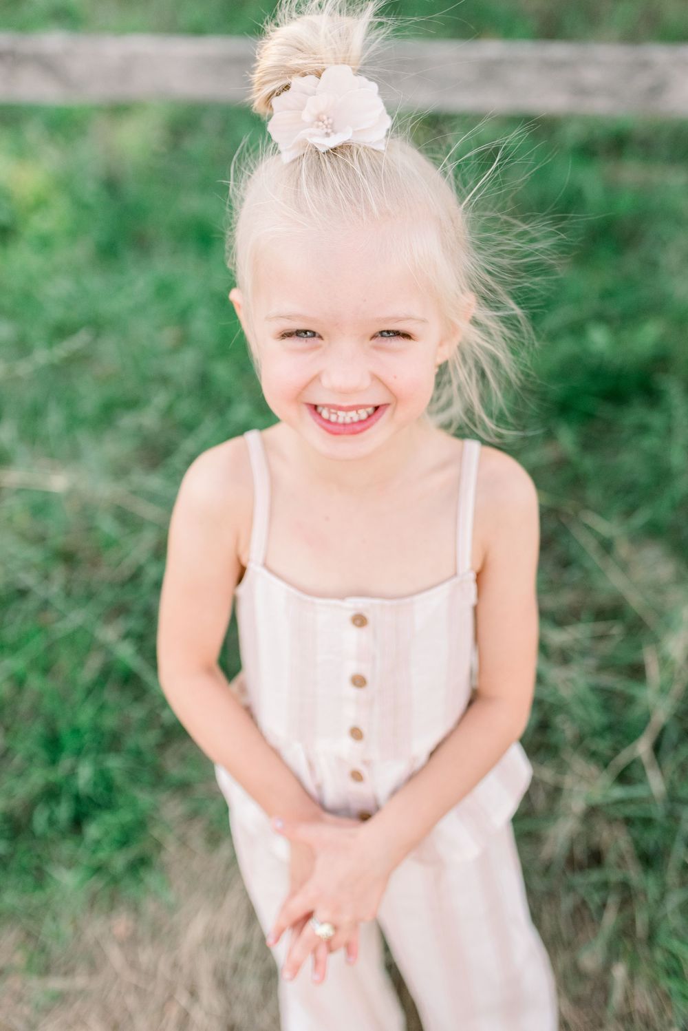 Young child in a white summer dress plays outdoors in a natural setting.