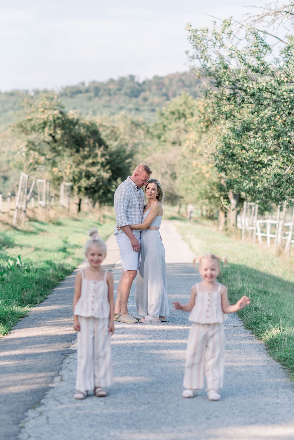 Family enjoying a casual stroll together on a gravel path with white fencing and trees.
