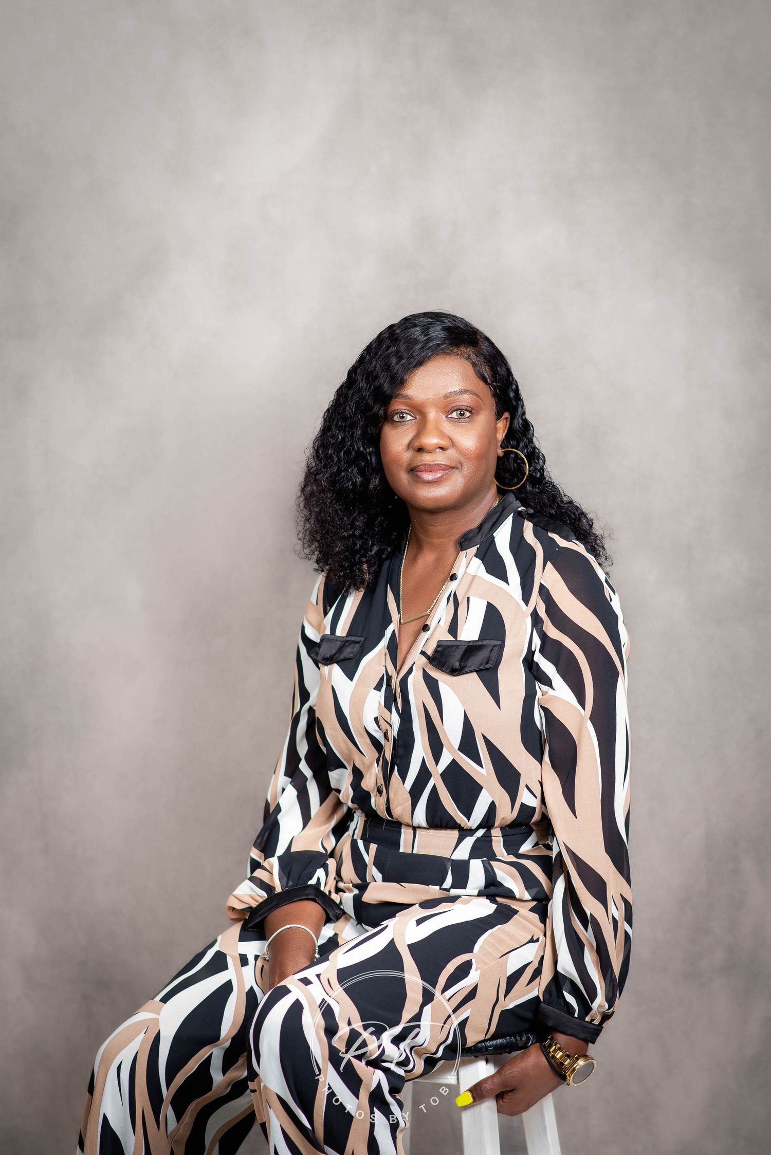 Studio portrait of woman wearing patterned wrap dress against gray background.