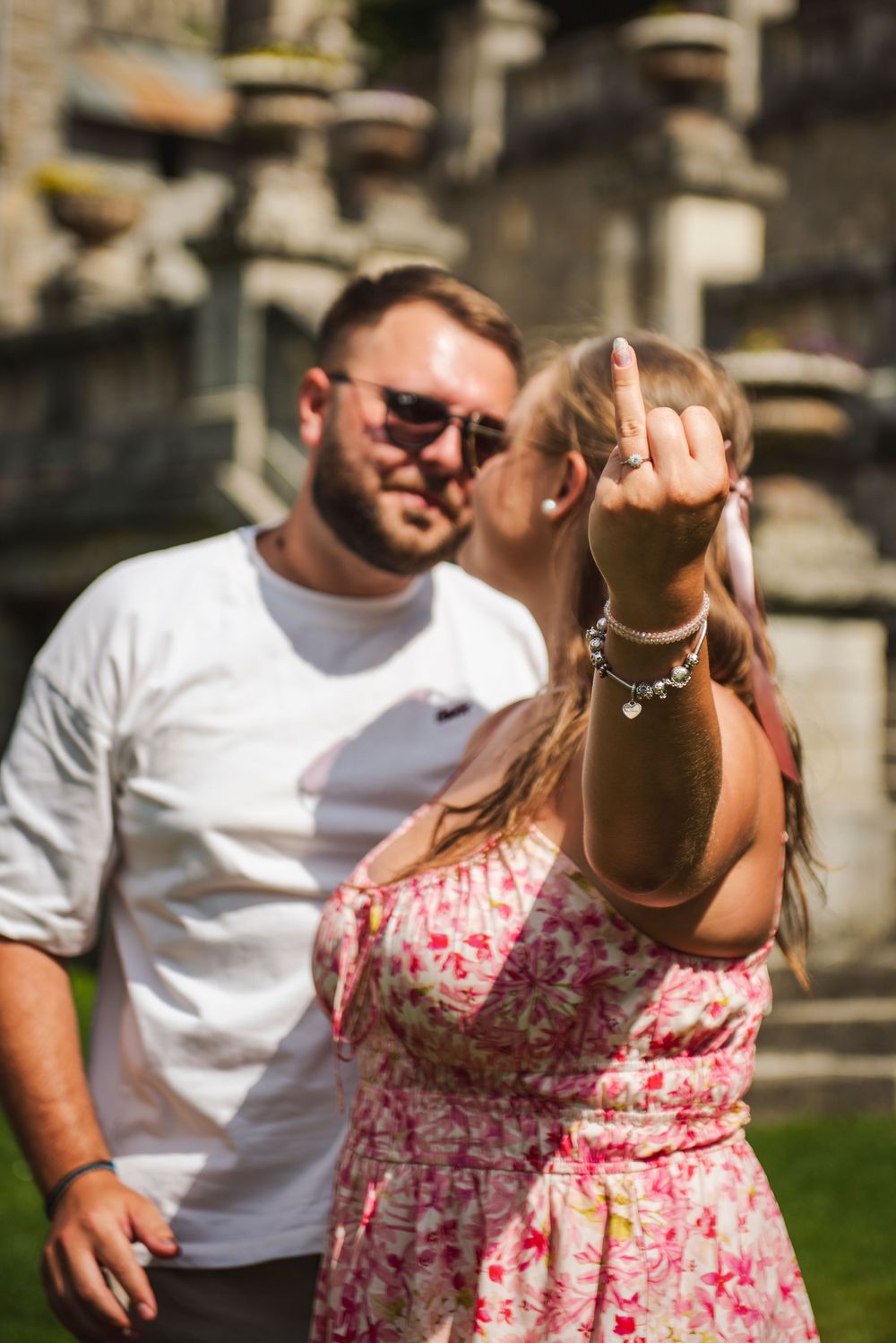 A couple in a park shares a playful moment as they dance together on a sunny day.
