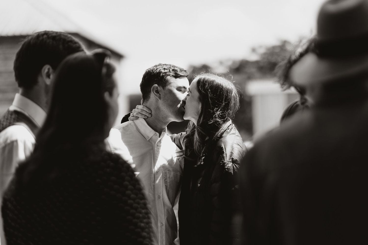 A black and white photograph shows contrasting scenes of people in various candid moments with couple kissing during drinks reception