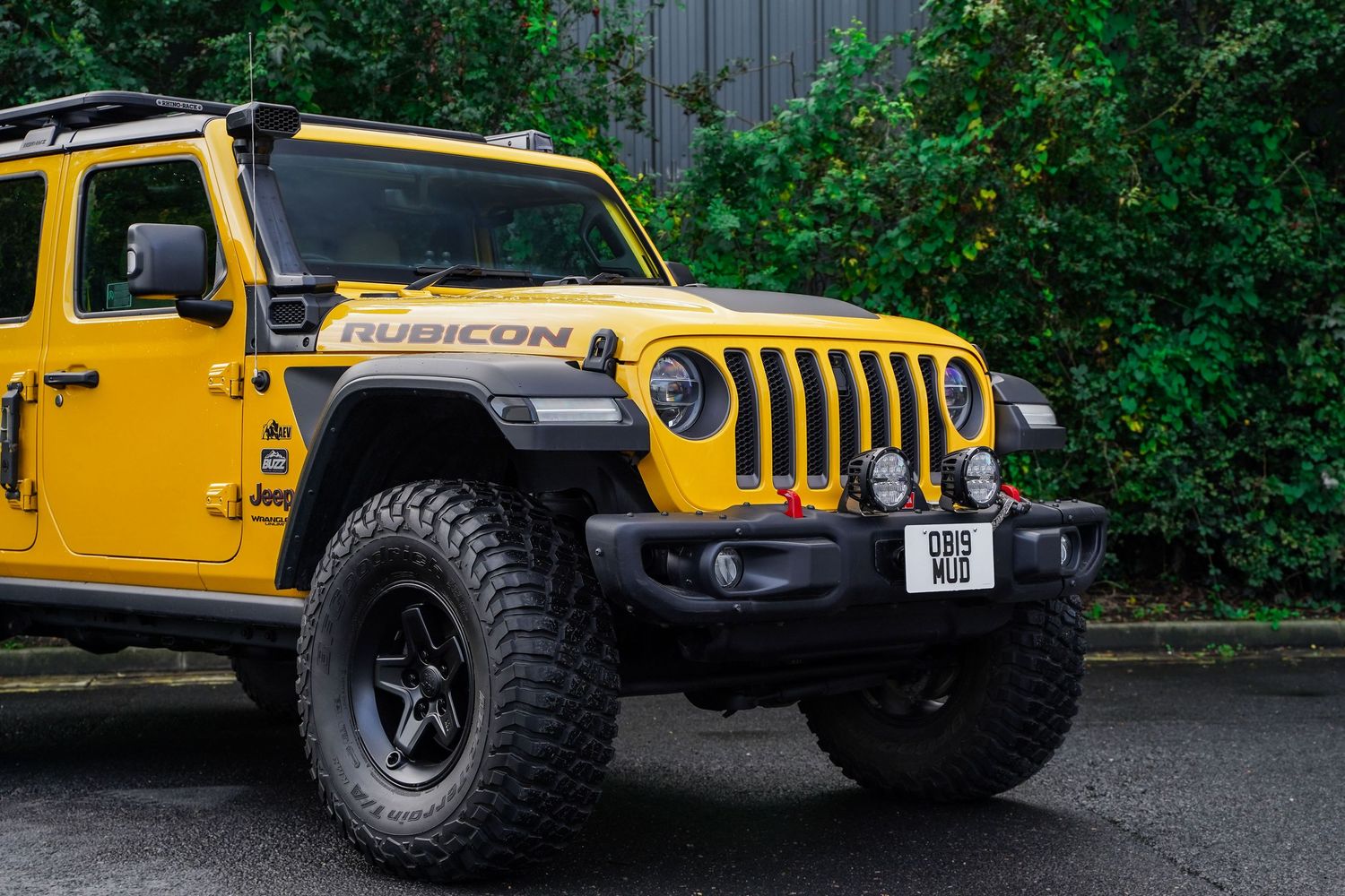 Front view of a yellow Jeep Wrangler with custom off-road modifications and auxiliary lights.