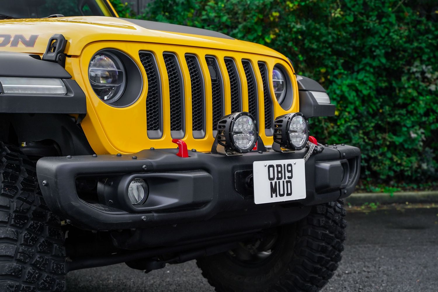 Detailed view of yellow Jeep's front end showing iconic seven-slot grille and fog lights.
