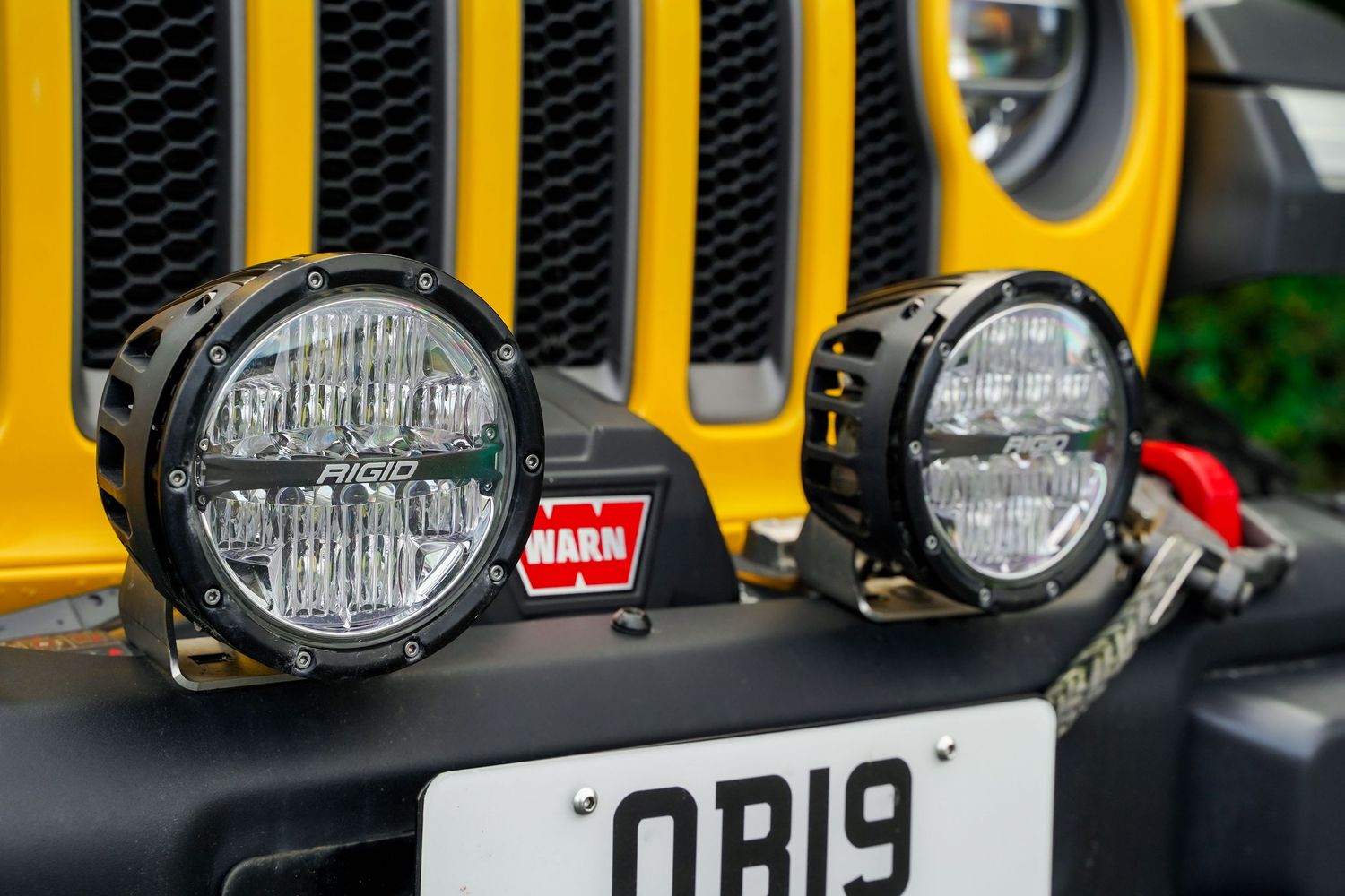 Close-up of yellow Jeep Wrangler's front grille and auxiliary lighting setup.