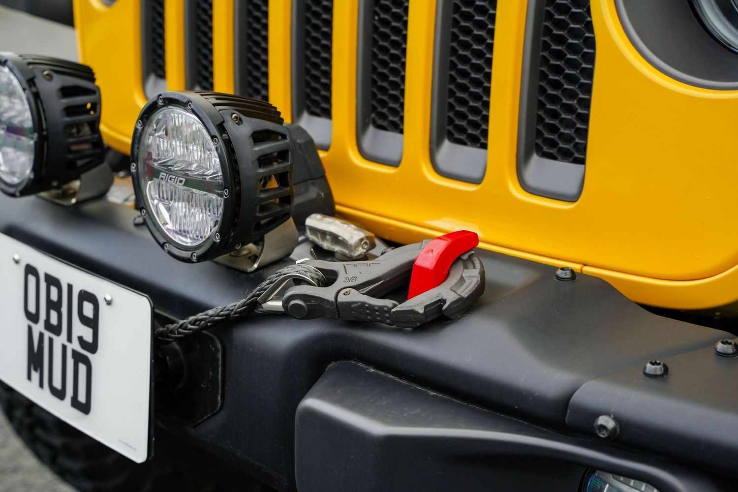 Close-up shot of yellow Jeep's grille and headlight assembly with custom lighting modifications.