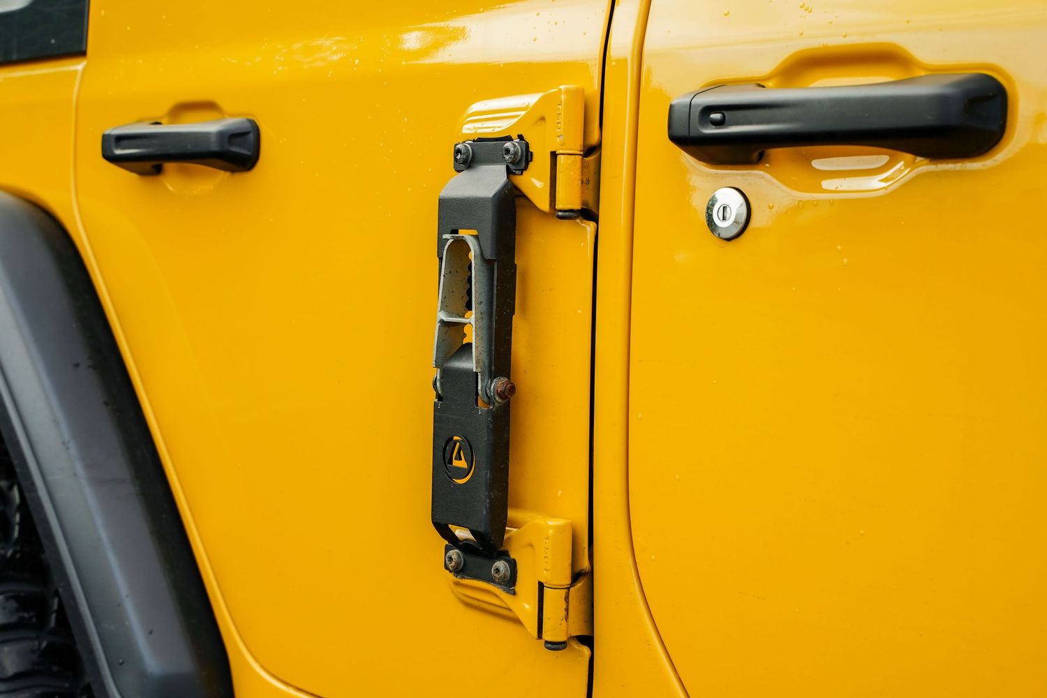 Detail shot of yellow Jeep Wrangler's door handles and side panels.