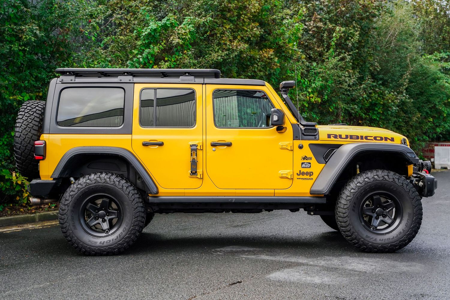 Profile view of a modified yellow Jeep Wrangler with lifted suspension and oversized tires.